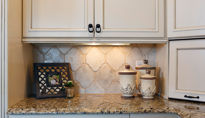 Look closely for some of the best details in this kitchen refresh: The cabinets, formerly a buttery yellow, were refinished and glazed, and hardware updated from silver to oil-rubbed bronze. The backsplash, updated with handmade tile from California, “spoke to me,” says homeowner Gretchen Cooling. Designer Vicky Serany notes that the tile is neutral, but has great texture and adds visual interest.