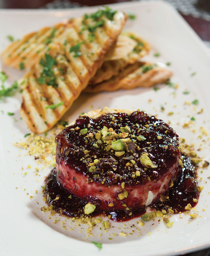 Grilled brie appetizer is served with a port wine raspberry reduction, toasted pistachio nuts and grilled toast points at Academy Street Bistro.