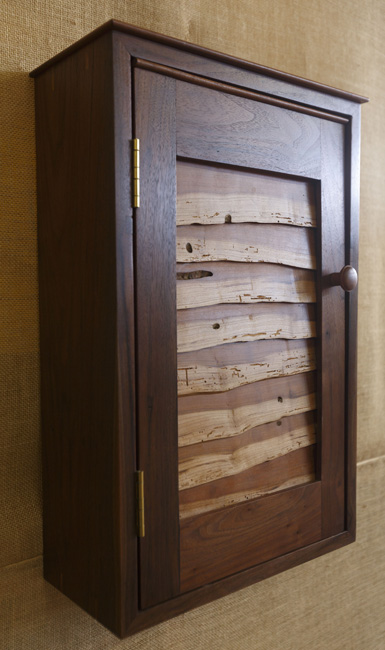 A live edge cherry panel in this black walnut wall cabinet shows the distinctive look of Live Edge Wood Designs.
