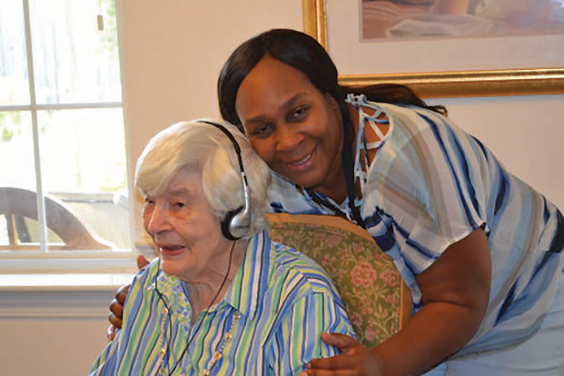 Music is making a big impact in the life of Beverly Norenton, seated, and others with memory impairment, through the Music & Memory program provided by the Holly Springs and Apex Sunrise Rotary Clubs to six local senior communities including Carillon Assisted Living in Fuquay-Varina. Assisting Norenton is Carillon staffer Shawanda Jones. 