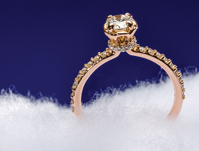 This 14K rose gold engagement ring from J.M. Edwards has a large center stone and smaller diamonds on the band.